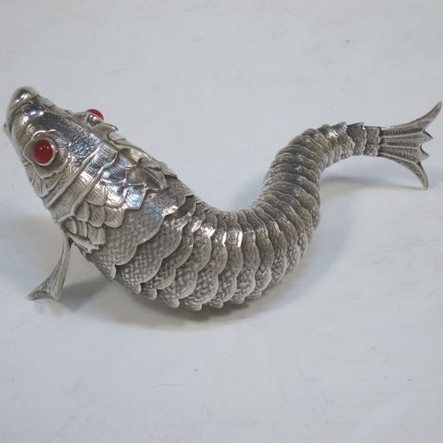 A very pretty Antique Edwardian Silver Articulated fish, having hand-chased scales and fins, and with two red glass eyes (possibly garnets). Made in Spain in ca. 1900. On one of the lower fins you can see the hallmark of a Pentagram that is a Spanish quality mark indicating a minimum of 915 Silver purity (Sterling Standard is 925). The dimensions of this fine hand-made antique Articulated Silver fish are length 17 cms (6.75 inches), height 5.5 cms (2.25 inches), and it weighs approx. 92g (3 troy ounces).   
