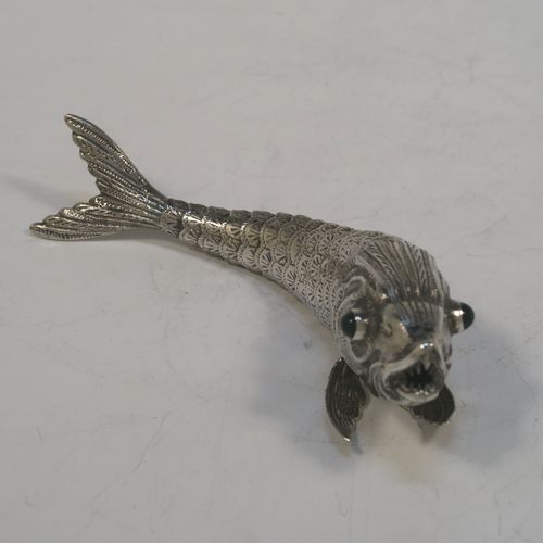 A very pretty Antique Edwardian Silver Articulated fish, having hand-chased scales and fins, and with two green glass eyes. This beautiful articulated silver fish model was made in Cordoba, Spain in ca. 1940. On one of the lower fins you can see the hallmark of a Pentagram that is a Spanish quality mark indicating a minimum of 915 Silver purity (Sterling Standard is 925), and in a separate mark the letters CO representing Cordoba. The dimensions of this fine hand-made antique Articulated Silver fish are length 15 cms (6 inches), height 4 cms (1.5 inches), and it weighs approx. 72g (2.3 troy ounces).   