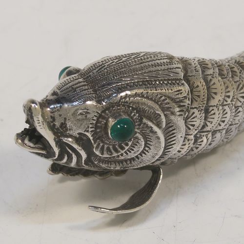 A very pretty Antique Edwardian Silver Articulated fish, having hand-chased scales and fins, and with two green glass eyes. This beautiful articulated silver fish model was made in Cordoba, Spain in ca. 1940. On one of the lower fins you can see the hallmark of a Pentagram that is a Spanish quality mark indicating a minimum of 915 Silver purity (Sterling Standard is 925), and in a separate mark the letters CO representing Cordoba. The dimensions of this fine hand-made antique Articulated Silver fish are length 15 cms (6 inches), height 4 cms (1.5 inches), and it weighs approx. 72g (2.3 troy ounces).