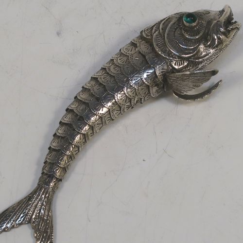 A very pretty Antique Edwardian Silver Articulated fish, having hand-chased scales and fins, and with two green glass eyes. This beautiful articulated silver fish model was made in Cordoba, Spain in ca. 1940. On one of the lower fins you can see the hallmark of a Pentagram that is a Spanish quality mark indicating a minimum of 915 Silver purity (Sterling Standard is 925), and in a separate mark the letters CO representing Cordoba. The dimensions of this fine hand-made antique Articulated Silver fish are length 15 cms (6 inches), height 4 cms (1.5 inches), and it weighs approx. 72g (2.3 troy ounces).