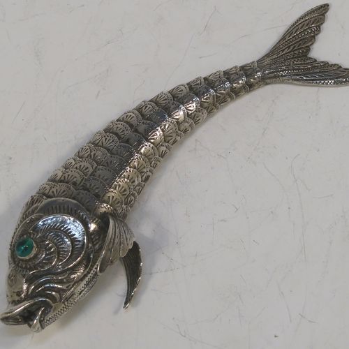 A very pretty Antique Edwardian Silver Articulated fish, having hand-chased scales and fins, and with two green glass eyes. This beautiful articulated silver fish model was made in Cordoba, Spain in ca. 1940. On one of the lower fins you can see the hallmark of a Pentagram that is a Spanish quality mark indicating a minimum of 915 Silver purity (Sterling Standard is 925), and in a separate mark the letters CO representing Cordoba. The dimensions of this fine hand-made antique Articulated Silver fish are length 15 cms (6 inches), height 4 cms (1.5 inches), and it weighs approx. 72g (2.3 troy ounces).