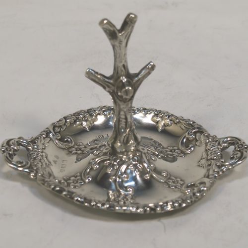 A very pretty Antique Victorian Sterling Silver ring tree, having a central naturalistic tree for rings sitting on a round base with two side-handles, with hand-chased floral and scroll decoration. This beautiful silver ring tree and base was made by Henry Matthews of Birmingham in 1900. The dimensions of this fine hand-made antique silver tree ring are height 7.5 cms (3 inches), diameter 8 cms (3 inches), and it weighs approx. 36g (1.2 troy ounce).   