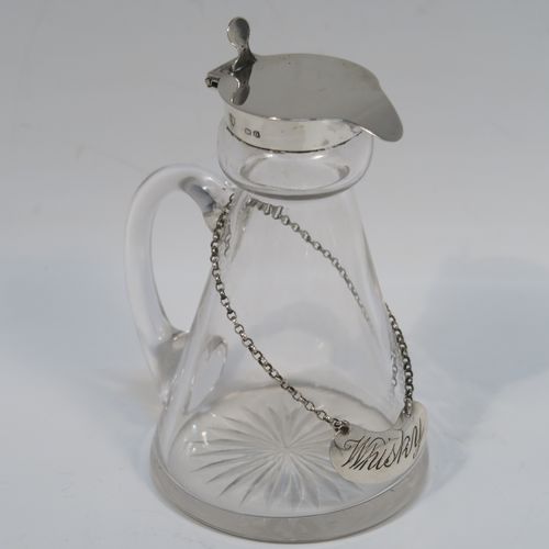 A handsome Antique Sterling Silver whisky toddy or noggin, having a round based hand-cut crystal body with tapering sides and loop handle, mounted with a silver collar and hinged flat lid with thumb-piece, all sitting on a flat star-cut base, and together with its original silver whisky label on a chain. This elegant silver and crystal whisky toddy was made by M and S Ltd. of Birmingham in 1913. The dimensions of this fine hand-made silver and crystal whisky noggin or toddy is height 11.5 cms (4.5 inches), and diameter at bases 7 cms (2.75 inches).  