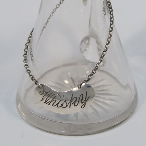 A handsome Antique Sterling Silver whisky toddy or noggin, having a round based hand-cut crystal body with tapering sides and loop handle, mounted with a silver collar and hinged flat lid with thumb-piece, all sitting on a flat star-cut base, and together with its original silver whisky label on a chain. This elegant silver and crystal whisky toddy was made by M and S Ltd. of Birmingham in 1913. The dimensions of this fine hand-made silver and crystal whisky noggin or toddy is height 11.5 cms (4.5 inches), and diameter at bases 7 cms (2.75 inches).