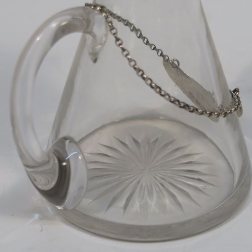 A handsome Antique Sterling Silver whisky toddy or noggin, having a round based hand-cut crystal body with tapering sides and loop handle, mounted with a silver collar and hinged flat lid with thumb-piece, all sitting on a flat star-cut base, and together with its original silver whisky label on a chain. This elegant silver and crystal whisky toddy was made by M and S Ltd. of Birmingham in 1913. The dimensions of this fine hand-made silver and crystal whisky noggin or toddy is height 11.5 cms (4.5 inches), and diameter at bases 7 cms (2.75 inches).
