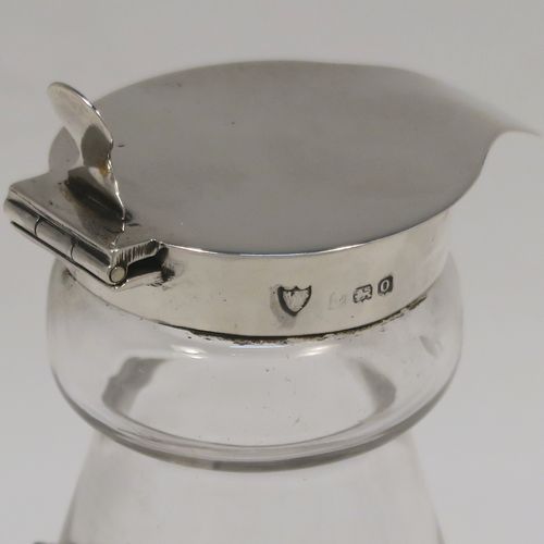 A handsome Antique Sterling Silver whisky toddy or noggin, having a round based hand-cut crystal body with tapering sides and loop handle, mounted with a silver collar and hinged flat lid with thumb-piece, all sitting on a flat star-cut base, and together with its original silver whisky label on a chain. This elegant silver and crystal whisky toddy was made by M and S Ltd. of Birmingham in 1913. The dimensions of this fine hand-made silver and crystal whisky noggin or toddy is height 11.5 cms (4.5 inches), and diameter at bases 7 cms (2.75 inches).