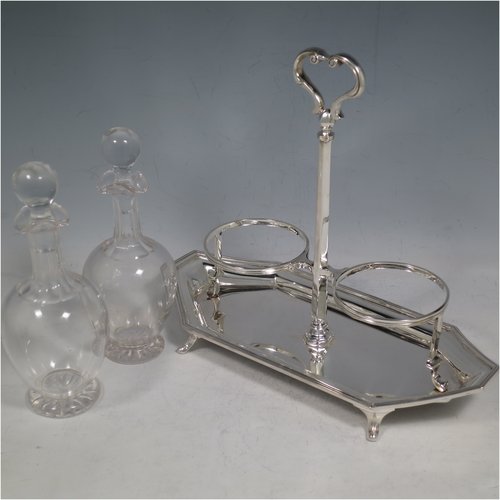 A Sterling Silver oil and vinegar set, having an octagonal boat-shaped body with applied reed-edged borders, a two-bottle frame with loop handle, a pair of hand-cut round crystal bottles with stoppers, and all sitting on four cast scroll feet. Made by Goldsmiths & Silversmiths of London in 1929. The dimensions of this fine hand-made silver oil and vinegar set are length 23 cms (9 inches), height 20 cms (8 inches), width 10 cms (4 inches), and the base weighs approx. 495g (16 troy ounces).