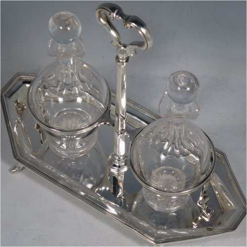 A Sterling Silver oil and vinegar set, having an octagonal boat-shaped body with applied reed-edged borders, a two-bottle frame with loop handle, a pair of hand-cut round crystal bottles with stoppers, and all sitting on four cast scroll feet. Made by Goldsmiths & Silversmiths of London in 1929. The dimensions of this fine hand-made silver oil and vinegar set are length 23 cms (9 inches), height 20 cms (8 inches), width 10 cms (4 inches), and the base weighs approx. 495g (16 troy ounces).
