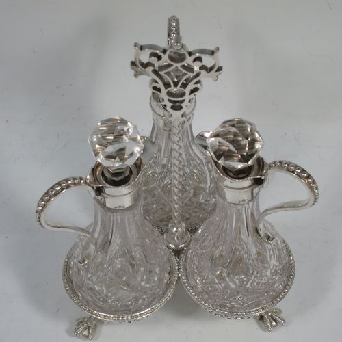 A very pretty Antique Victorian Sterling Silver oil and vinegar set, having three hand-cut crystal bottles with silver mounts, stoppers, and bead-edged scroll handles. All sitting in a hand-pierced frame with matching bead-work, a twisted central and hand-pierced handle, and all sitting on three cast claw and ball feet. Made by Martin Hall and Co., of Sheffield in 1857. The dimensions of this fine hand-made antique silver and crystal oil and vinegar set are height 19 cms (7.5 inches), width 11 cms (4.3 inches), and the frame  weighs approx. 170g (5.5 troy ounces).    