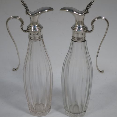 A very handosme Antique Sterling Silver oil and vinegar set in a neoclassical style, having an oval boat-shaped body with applied reed-edged borders, a two-bottle frame with hand-pierced handle, a pair of hand-cut round crystal bottles with panelled bodies and original hinged lid mounts with scroll handles, and all sitting on four flange feet. Made by Goldsmiths & Silversmiths of Sheffield in 1919. The dimensions of this fine hand-made antique silver oil and vinegar set are length 20 cms (8 inches), height 25.5 cms (10 inches), width 14 cms (5.5 inches), and it weighs approx. 250g (8 troy ounces).    