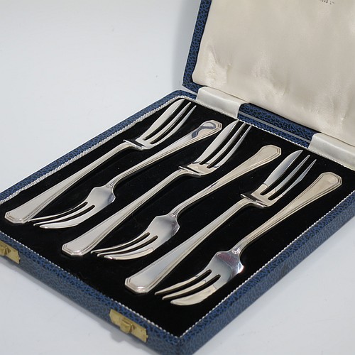 A Sterling Silver Art Deco style set of six pastry forks, having a double-struck plain reeded Athenian pattern handle, and three tined forks, all in their original cream satin and black velvet-lined presentation box. Made by Mappin and Webb of Sheffield in 1963. The dimensions of these fine hand-made silver pastry forks are length 13 cms (5.25 inches), and they weigh a total of 103g (3.3 troy ounces).