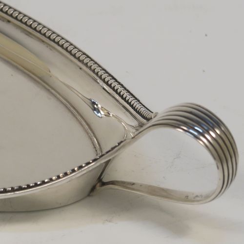 A very handsome Antique Georgian Sterling Silver pen tray, having a very plain oval body with applied beaded borders, with looped and reeded side-handles, and all sitting on a flat base. This elegant antique silver pen tray was made by John Schofield of Lndon in 1779. The dimensions of this fine hand-made antique silver pen tray are length 25.5 cms (10 inches), width 9.5 cms (3.75 inches), and it weighs approx. 138g (4.5 troy ounces).