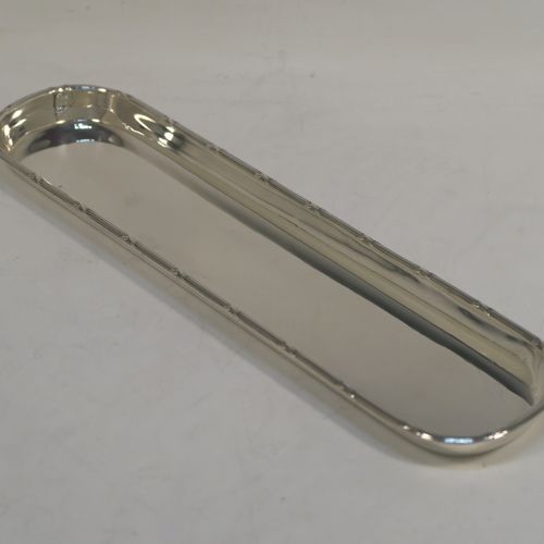 A very elegant Antique Sterling Silver pen tray, having a very plain rectangular body with rounded ends, an applied reed and ribbon border, and all sitting on a flat base. This handsome silver pen tray was made by Stokes and Ireland of Chester in 1914. The dimensions of this fine hand-made antique silver pen tray are length 24 cms (9.5 inches), width 6.5 cms (2.5 inches), and it weighs approx. 108g (3.5 troy ounces).