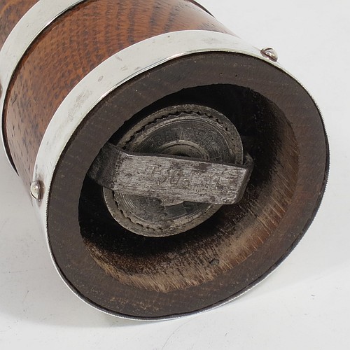 A handsome Sterling Silver and wooden pepper grinder in a milk churn style, having a plain tapering straight sided body with three applied and pinned silver bands, a knurled round finial, and an original Peugeot grinder mechanism. Made by Hukin and Heath of Birmingham in 1929. The dimensions of this fine hand-made silver and wooden pepper grinder are height 10 cms (4 inches), and diameter at base 5 cms (2 inches).    