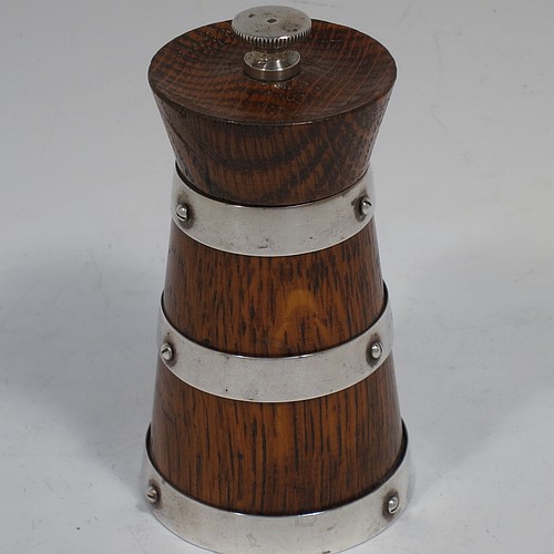 A handsome Sterling Silver and wooden pepper grinder in a milk churn style, having a plain tapering straight sided body with three applied and pinned silver bands, a knurled round finial, and an original Peugeot grinder mechanism. Made by Hukin and Heath of Birmingham in 1929. The dimensions of this fine hand-made silver and wooden pepper grinder are height 10 cms (4 inches), and diameter at base 5 cms (2 inches).    