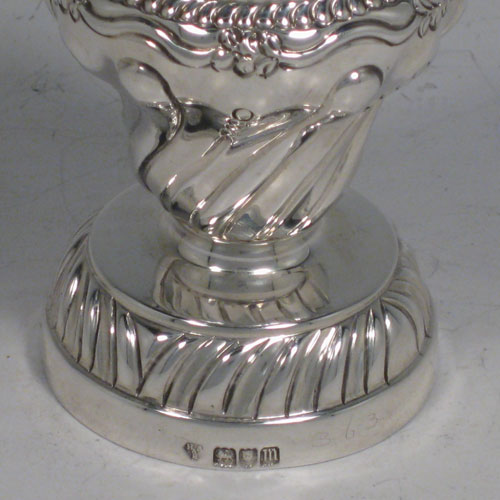 Antique Edwardian sterling silver pepper grinder, having a hand-chased body with floral decoration and swirl fluting, a cast floral finial, and sitting on a pedestal foot. Made in London in 1907. Height 12 cms (4.75 inches), diameter at base 5 cms (2 inches). Weight approx. 140g (4.5 troy ounces).