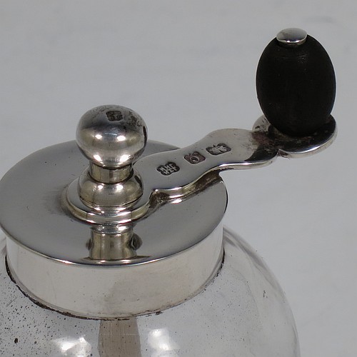 A handsome Antique Edwardian Sterling Silver and hand-blown crystal pepper grinder, having a plain round body with plain mounts top and bottom, a side-winding grinder arm with wooden finial, and an original Peugeot grinding mechanism. Made by Heath and Middleton of Birmingham in 1902. The dimensions of this fine hand-made antique silver and crystal pepper grinder are height 9.5 cms (3.75 inches), and diameter at base 5.5 cms (2.25 inches).    