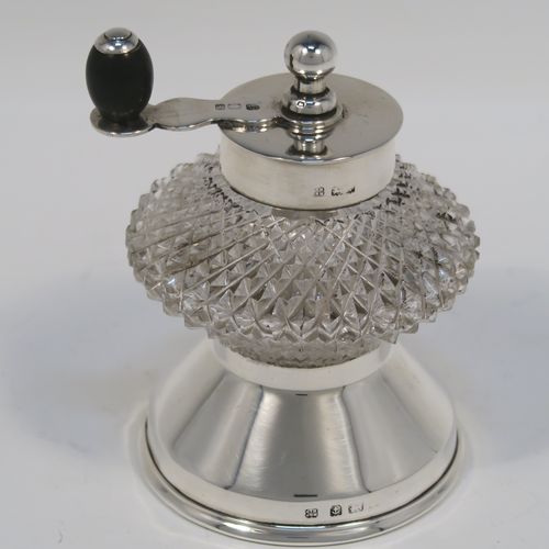 A handsome Antique Edwardian Sterling Silver and hand-cut crystal pepper grinder, having a round body with hobnail-cut pattern, plain round mounts top and bottom, a side-winding grinder arm with wooden finial, and an original Peugeot grinding mechanism. This elegant antique pepper grinder was made by Heath and Middleton of London in 1908. The dimensions of this fine hand-made silver and crystal pepper grinder are height 9 cms (3.5 inches), and diameter at base 6 cms (2.3 inches).   
