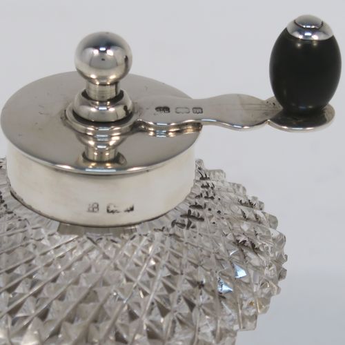 A handsome Antique Edwardian Sterling Silver and hand-cut crystal pepper grinder, having a round body with hobnail-cut pattern, plain round mounts top and bottom, a side-winding grinder arm with wooden finial, and an original Peugeot grinding mechanism. This elegant antique pepper grinder was made by Heath and Middleton of London in 1908. The dimensions of this fine hand-made silver and crystal pepper grinder are height 9 cms (3.5 inches), and diameter at base 6 cms (2.3 inches).