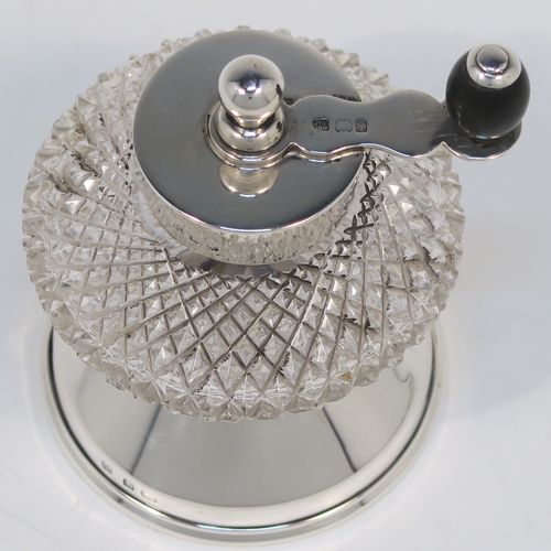A handsome Antique Edwardian Sterling Silver and hand-cut crystal pepper grinder, having a round body with hobnail-cut pattern, plain round mounts top and bottom, a side-winding grinder arm with wooden finial, and an original Peugeot grinding mechanism. This elegant antique pepper grinder was made by Heath and Middleton of London in 1908. The dimensions of this fine hand-made silver and crystal pepper grinder are height 9 cms (3.5 inches), and diameter at base 6 cms (2.3 inches).