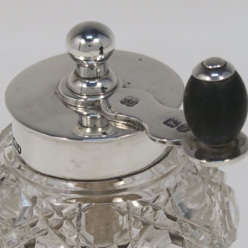 A handsome Antique Edwardian Sterling Silver and hand-cut crystal pepper grinder, having a round body with hobnail-cut pattern, plain round mounts top and bottom, a side-winding grinder arm with wooden finial, and an original Peugeot grinding mechanism. This elegant antique pepper grinder was made by Heath and Middleton of London in 1904. The dimensions of this fine hand-made silver and crystal pepper grinder are height 8.5 cms (3.3 inches), and diameter at base 5.5 cms (2.25 inches).