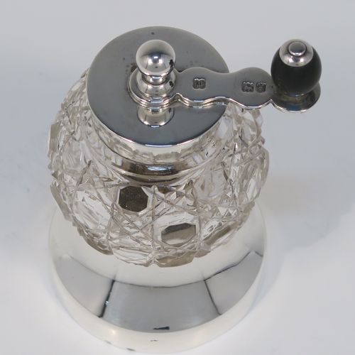 A handsome Antique Edwardian Sterling Silver and hand-cut crystal pepper grinder, having a round body with hobnail-cut pattern, plain round mounts top and bottom, a side-winding grinder arm with wooden finial, and an original Peugeot grinding mechanism. This elegant antique pepper grinder was made by Heath and Middleton of London in 1904. The dimensions of this fine hand-made silver and crystal pepper grinder are height 8.5 cms (3.3 inches), and diameter at base 5.5 cms (2.25 inches).
