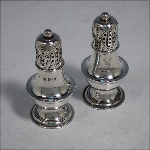 An Antique Victorian Sterling Silver pair of pepper pots, having plain round bellied bodies, with reeded borders, pull-off hand-pierced lids with ball finials, and sitting on pedestal feet. Made by Hilliard & Thomason of Birmingham in 1899. The dimensions of these fine hand-made antique silver pepper pots are height 7 cms (2.75 inches), diameter 3 cms (1.25 inches), and they weigh a total of approx. 43g (1.4 troy ounces). Please note that these items are crested.   