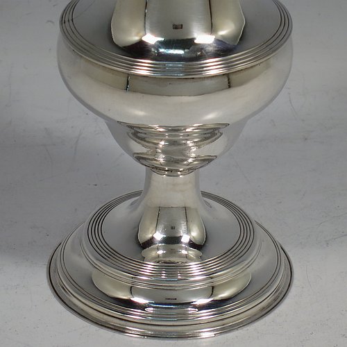 An Antique Georgian George II Sterling Silver pepper pot, having a plain bellied body with applied reeded borders, a hand-pierced pull-off lid with urn-shaped finial, and sitting on a pedestal foot. Made by Peter & William Bateman of London in 1807. The dimensions of this fine hand-made antique silver pepper pot are height 15 cms (6 inches), diameter of main body 5 cms (2 inches), and it weighs approx. 93g (3 troy ounces).