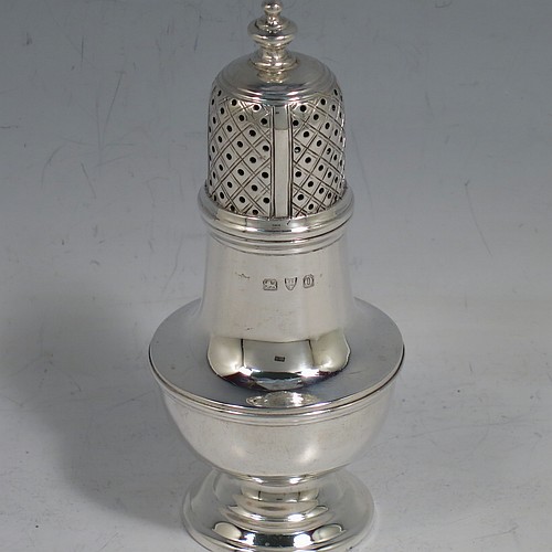An Antique Victorian Sterling Silver pepper shaker or pot in a George II style, having a plain round bellied body, with reeded borders, pull-off hand-pierced lid with a cast finial, and sitting on a pedestal foot. Made by Nathan & Hayes of Chester in 1897. The dimensions of this fine hand-made antique silver pepper pot or shaker are height 11 cms (4.3 inches), diameter 5 cms (2 inches), and it weighs approx. 85g (2.7 troy ounces).