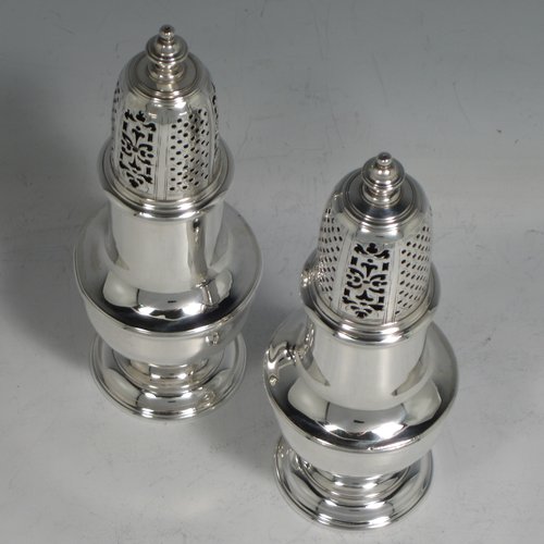 An Antique Georgian sterling silver pair of George II pepper pots, having plain round baluster bodies, with hand-pierced pull-off lids and finials, and sitting on pedestal feet. Made by Thomas Bamford I of London in 1730. The dimensions of these fine hand-made silver pepper pots are height 14.5 cms (5.75 inches), diameter of main body 5 cms (2 inches), and they weigh a total of approx. 257g (8.3 troy ounces).