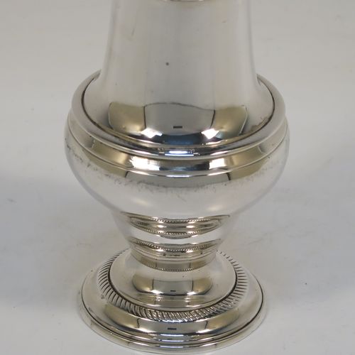 A handsome Antique Georgian Sterling Silver pepper pot, having a plain round bellied body, a hand-pierced pull-off lid with swirl finial, and sitting on a pedestal foot. This elegant antique silver pepper pot was made by John Delmester of London in 1764. The dimensions of this fine hand-made silver pepper pot are height 15 cms (6 inches), diameter of main body 5 cms (2 inches), and it weighs approx. 150g (4.8 troy ounces).