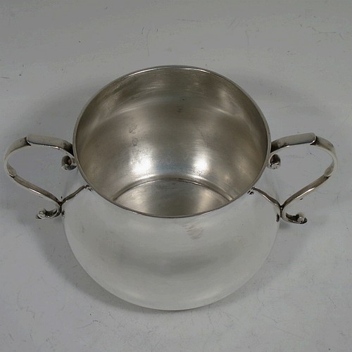 A very handsome Sterling Silver porringer, having a plain round bellied body, two scroll side handles, and sitting on a flat base. Made by Goldsmiths and Silversmiths of London in 1934. The dimensions of this fine hand-made silver porringer are height 7.5 cms (3 inches), spread across arms 13.5 cms (5.3 inches), and it weighs approx. 185g (6 troy ounces).