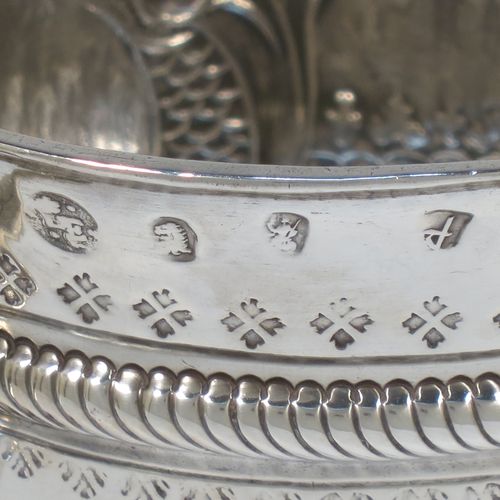 A very handsome Antique Queen Anne Britannia Standard Silver porringer, having a round bellied body with hand-chased fluted and scroll decoration, with a round cartouche on one side, two scroll side-handles, and sitting on a flat base. Made by Timothy Ley of London in 1714. The dimensions of this fine hand-made antique Britannia silver porringer are height 11 cms (4.25 inches), spread across handles 18 cms (7 inches), and it weighs approx. 284g (9 troy ounces). Please note that this item has an engraved contemporaneous set of initials in the cartouche.