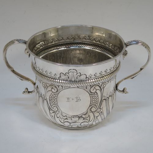 A very handsome Antique Queen Anne Britannia Standard Silver porringer, having a round bellied body with hand-chased fluted and scroll decoration, with a round cartouche on one side, two scroll side-handles, and sitting on a flat base. Made by Timothy Ley of London in 1714. The dimensions of this fine hand-made antique Britannia silver porringer are height 11 cms (4.25 inches), spread across handles 18 cms (7 inches), and it weighs approx. 284g (9 troy ounces). Please note that this item has an engraved contemporaneous set of initials in the cartouche.