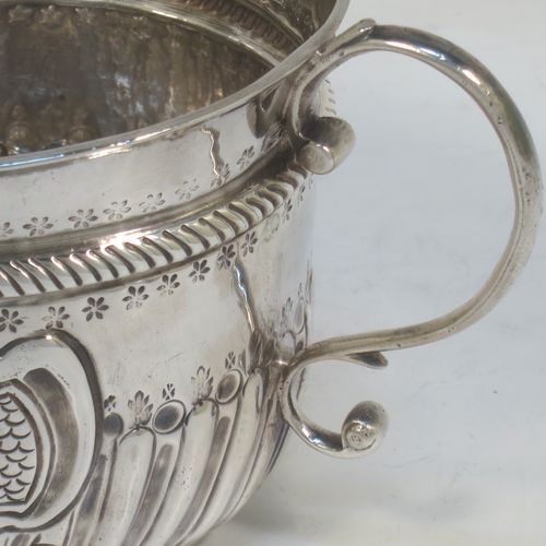 A very handsome Antique Queen Anne Britannia Standard Silver porringer, having a round bellied body with hand-chased fluted and scroll decoration, with a round cartouche on one side, two scroll side-handles, and sitting on a flat base. Made by Seth Lofthouse (Prob.) of London in 1709. The dimensions of this fine hand-made antique Britannia silver porringer are height 8 cms (3 inches), spread across handles 16 cms (6.25 inches), and it weighs approx. 156g (5 troy ounces).
