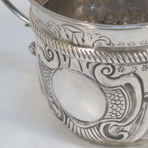A very handsome Antique Queen Anne Britannia Standard Silver porringer, having a round bellied body with hand-chased fluted and scroll decoration, with a round cartouche on one side, two scroll side-handles, and sitting on a flat base. Made by Seth Lofthouse (Prob.) of London in 1709. The dimensions of this fine hand-made antique Britannia silver porringer are height 8 cms (3 inches), spread across handles 16 cms (6.25 inches), and it weighs approx. 156g (5 troy ounces).