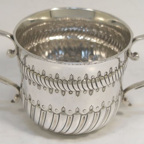 A very handsome Antique Edwardian Sterling Silver porringer, having a round bellied body with bands of hand-chased fluted decoration, two scroll side-handles, and sitting on a flat base. This elegant silver poringer was made by D. and J. Welby of London in 1906. The dimensions of this fine hand-made antique silver porringer are height 7 cms (2.75 inches), spread across handles 14 cms (5.5 inches), and it weighs approx. 182g (5.9 troy ounces).  