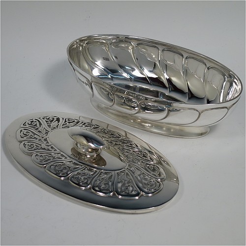 An Antique Edwardian Sterling Silver pot pourri holder, having an oval body with hand-chased fluted decoration, a lift-off lid with a cast oval handle and hand-pierced floral and scroll work, all sitting on an oval collet foot. Made by Walker and Hall of Sheffield in 1908. The dimensions of this fine hand-made antique silver pot-pourri holder are length 16 cms (6.5 inches), width height 9 cms (3.5 inches), height 7 cms (2.75 inches), and it weighs approx. 308g (10 troy ounces)