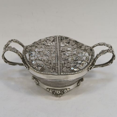 A very unusual Antique Edwardian Sterling Silver pot pourri holder, having a uniquely designed etched crystal main body with a plain rim mount, attached to which is a double hinged and pierced cover with beautiful hand-made and applied three-leaf clover decoration, together with two double-loop side-handles, and sitting on four cast floral feet. This beautiful antique silver pot-pourri holder was made by William Comyns of London in 1908. The dimensions of this fine hand-made silver pot-pourri dish are 6.5cm (2.5 inches) tall, by 16cm (6.5 inches) from handle to handle, and 10cm (4 inches) deep.  