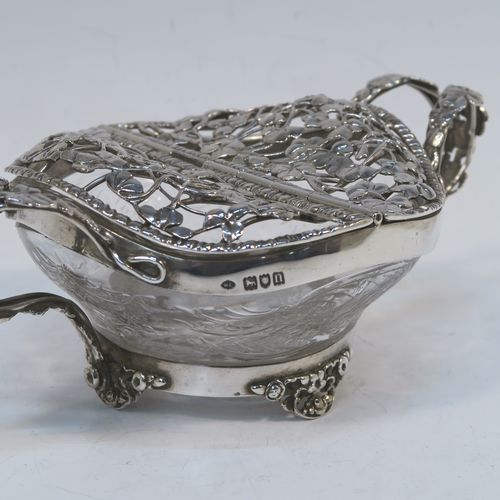 A very unusual Antique Edwardian Sterling Silver pot pourri holder, having a uniquely designed etched crystal main body with a plain rim mount, attached to which is a double hinged and pierced cover with beautiful hand-made and applied three-leaf clover decoration, together with two double-loop side-handles, and sitting on four cast floral feet. This beautiful antique silver pot-pourri holder was made by William Comyns of London in 1908. The dimensions of this fine hand-made silver pot-pourri dish are 6.5cm (2.5 inches) tall, by 16cm (6.5 inches) from handle to handle, and 10cm (4 inches) deep.