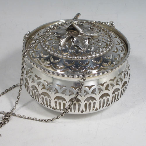 Antique Edwardian sterling silver pot pourri holder, having a round bellied hand-pierced body, a pull-off lid with cast floral finial, and an attached triple chain and hook. Made by Skinner and Co., of London in 1910. The dimensions of this fine hand-made silver pot-pourri holder are diameter 10 cms (4 inches), height 8.5 cms (3.25 inches), and it weighs approx. 204g (6.6 troy ounces).