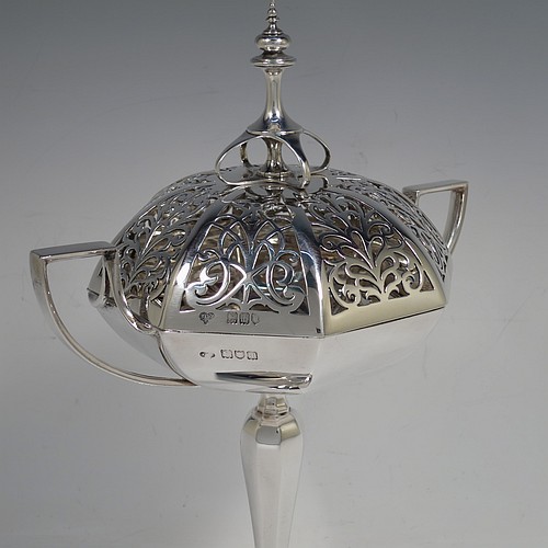 A very handsome and large Antique Edwardian Sterling Silver pot pourri holder in an Art Nouveau style, having an unusual trophy shaped body with two-side-handles, a lift off hand-pierced and panelled lid with cast urn-shaped finial, and all sitting on an octagonal pedestal foot. Made by Goldsmiths and Silversmiths of London in 1907. The dimensions of this fine hand-made antique silver pot-pourri holder are height 28 cms (11 inches), spread across arms 18.5 cms (7.25 inches), and it weighs approx. 482g (15.5 troy ounces)