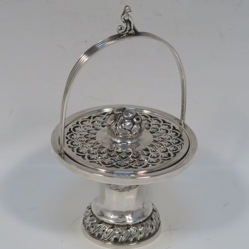 A beautiful Antique Edwardian Sterling Silver pot pourri holder, having a round panelled body and pedestal foot, a reeded loop carrying handle, and a pull-off lid with hand-pierced decoration surrounding a round cast floral finial. This pretty pot-pourri covered dish was made by Sharman D. Neill of Chester in 1910. The dimensions of this fine hand-made antique silver pot-pourri holder are height (inc. handle) 14 cms (5.5 inches), diameter of main body 8.5 cms (3.3 inches), and it weighs approx. 109g (3.5 troy ounces).   