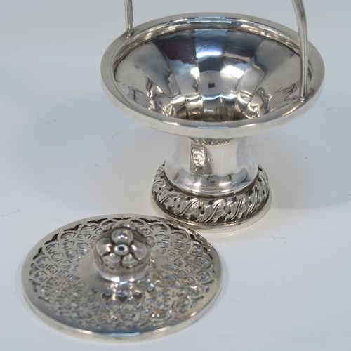 A beautiful Antique Edwardian Sterling Silver pot pourri holder, having a round panelled body and pedestal foot, a reeded loop carrying handle, and a pull-off lid with hand-pierced decoration surrounding a round cast floral finial. This pretty pot-pourri covered dish was made by Sharman D. Neill of Chester in 1910. The dimensions of this fine hand-made antique silver pot-pourri holder are height (inc. handle) 14 cms (5.5 inches), diameter of main body 8.5 cms (3.3 inches), and it weighs approx. 109g (3.5 troy ounces).
