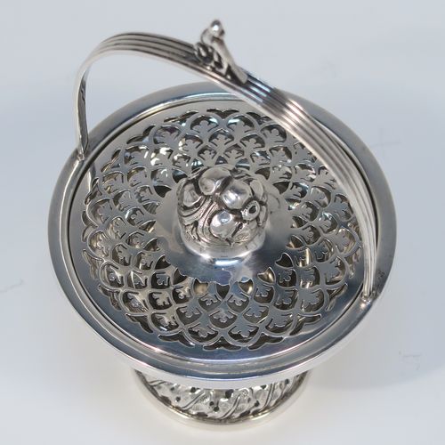 A beautiful Antique Edwardian Sterling Silver pot pourri holder, having a round panelled body and pedestal foot, a reeded loop carrying handle, and a pull-off lid with hand-pierced decoration surrounding a round cast floral finial. This pretty pot-pourri covered dish was made by Sharman D. Neill of Chester in 1910. The dimensions of this fine hand-made antique silver pot-pourri holder are height (inc. handle) 14 cms (5.5 inches), diameter of main body 8.5 cms (3.3 inches), and it weighs approx. 109g (3.5 troy ounces).