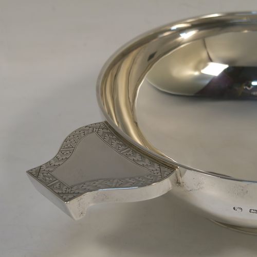 A large and handsome Sterling Silver quaich, having a very plain round body, with two side handles having hand-engraved geometrical engraving, and sitting on a collet foot. This elegant silver quaich was made by Robert Stebbings of London in 1927. The dimensions of this fine hand-made sterling silver quaich are diameter of body 18 cms (7 inches), height 6.5 cms (2.5 inches), and it weighs approx. 423g (13.6 troy ounces).