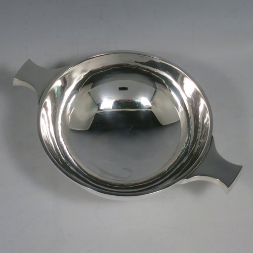 A Sterling Silver Scottish quaich, having a very plain round body, with two side handles, sitting on a collet foot. Made by Hamilton & Inches of Edinburgh in 1977. The dimensions of this fine hand-made silver quaich are diameter of body 13 cms (5 inches), height 5 cms (2 inches), and it weighs approx. 217g (7 troy ounces).