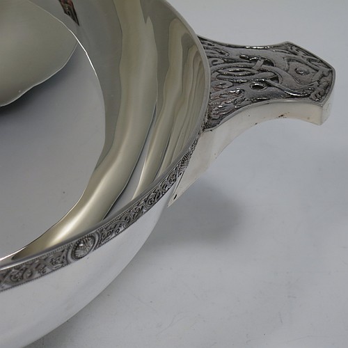 A very large and handsome Sterling Silver Celtic quaich, having a very plain round body, with two cast side handles in a Celtic style, a matching applied border, and sitting on a collet foot. Made by Wakely & Wheeler of London in 1988. The dimensions of this fine hand-made silver Celtic quaich are diameter of body 25 cms (10 inches), height 9 cms (3.5 inches), and it weighs approx. 925g (30 troy ounces).