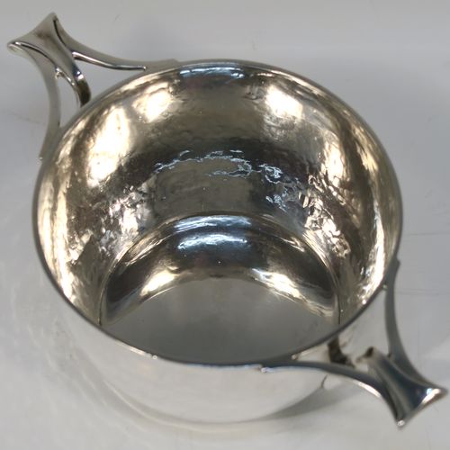 An unusual Antique Edwardian Sterling silver Arts & Crafts style Quaich, having a round bellied body with hand-hammered decoration, with two pierced tendril style side-handles, and all sitting on a flat base. This elegant silver quaich style bowl was made by D. and J. Welby of London in 1903. The dimensions of this fine hand-made silver Arts and Crafts style quaich are diameter of body 10.5 cms (4.25 inches), height 6 cms (2.3 inches), and it weighs approx. 246g (7.9 troy ounces).