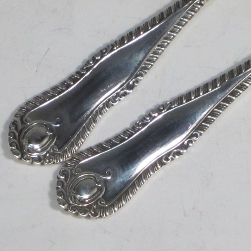 Sterling silver pair of salad servers, having very plain oval bowls, featuring long handles with hand-chased shaped gadroon an floral terminals. Made by Goldsmiths and Silversmiths of Sheffield in 1920. The length of these fine hand-made silver salad servers are 28 cms (11 inches), and the total weight is approx. 196g (6.3 troy ounces).